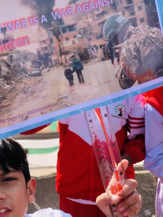 A peaceful child is holding a ruler to demonstrate sympathy with Palestinian children during a rally.
